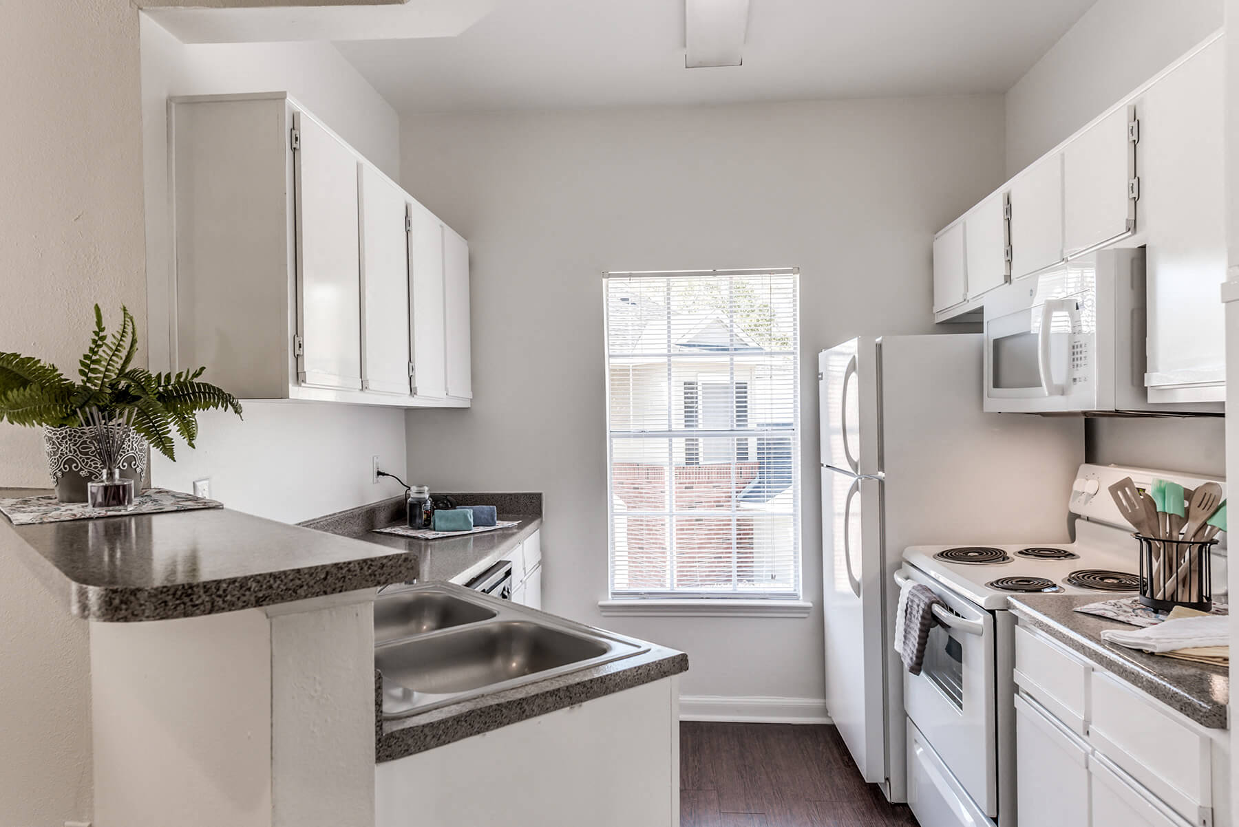 A bright kitchen with white appliances at the Hollow Creek apartments in Conroe, Texas.